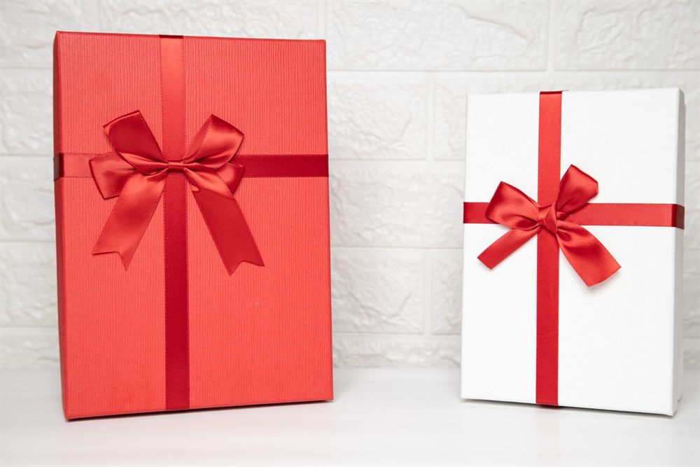 Two wrapped gift boxes with red satin ribbons
