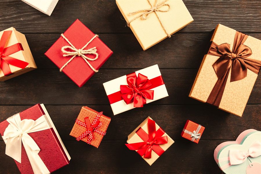 Assorted wrapped gifts with bows on a wooden table