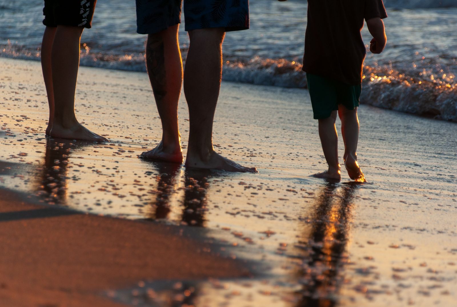 Family walking along the shoreline at sunset