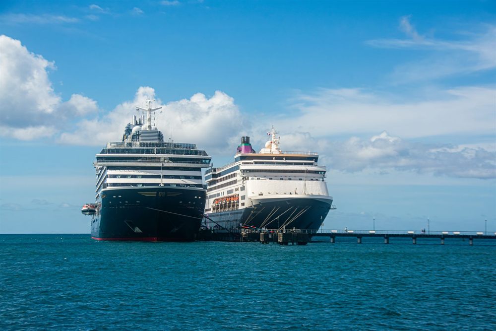 Two cruise ships docked at a sunny Caribbean harbor