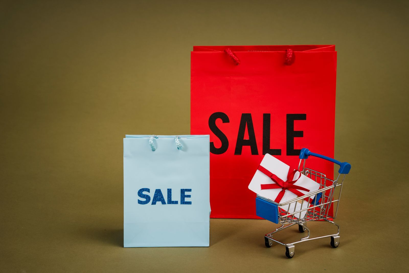 Shopping bags marked SALE with a gift in a small cart, like the extras bundled into cruise promotions